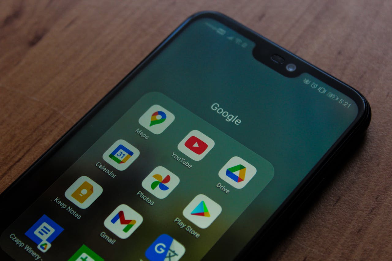 Close-up of a smartphone showing various Google apps on its screen.